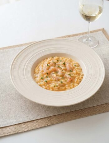 piatto di risotto cremoso agli scampi con bicchiere di vino