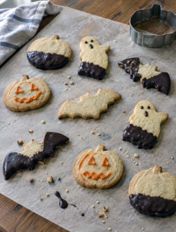 Biscotti di Halloween di frolla morbida a forma di zucca, fantasma e pipistrello, con cioccolato fondente e glassa arancione