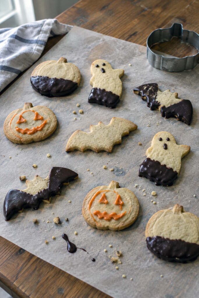 Biscotti di Halloween di frolla morbida a forma di zucca, fantasma e pipistrello, con cioccolato fondente e glassa arancione